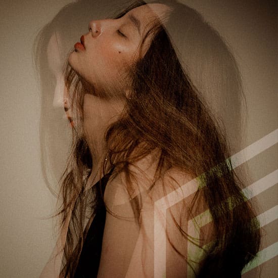 A woman with long hair is shown in profile against a neutral background. Her image is overlaid twofold, creating a sense of motion or duality. She appears to be leaning back with closed eyes, adding an artistic and ethereal quality to the photograph.