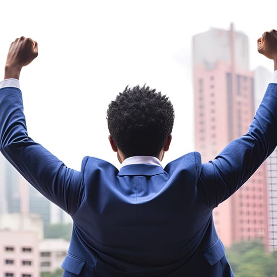Back view of a person in a blue suit with short curly hair raising their arms triumphantly. The setting is outdoors with skyscrapers in the background, indicating an urban environment. The mood suggests celebration or success.