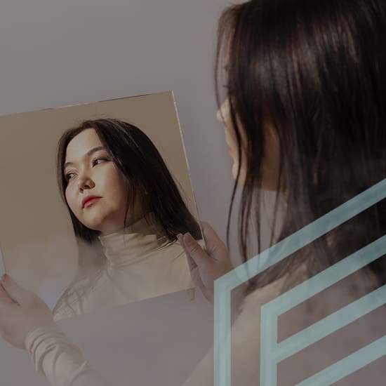 A woman with long dark hair holds a square mirror, reflecting her face. She wears a light-colored turtleneck and gazes thoughtfully into the mirror. The image includes an abstract geometric design overlay on the right side.