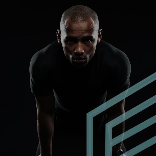 A person with a serious expression is seen from the waist up against a black background. They are wearing a dark, short-sleeved shirt and are slightly bent forward. A transparent geometric design overlays part of the image on the right.