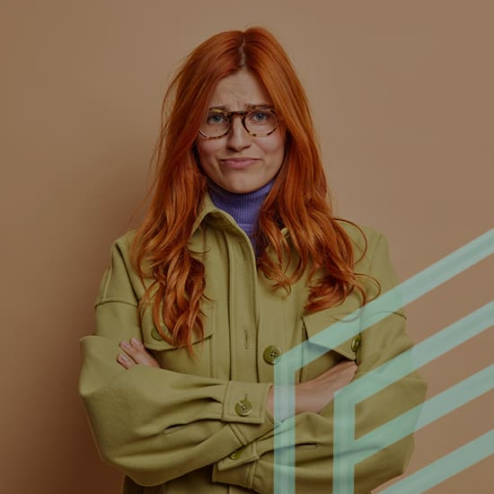 A woman with long red hair and glasses stands in front of a beige background. She is wearing a green jacket over a purple turtleneck and has her arms crossed, with a skeptical expression on her face. Pale green diagonal lines are partially overlaid on the image.