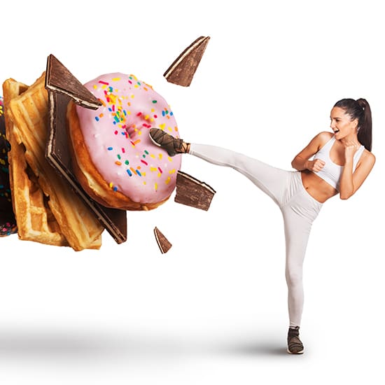 A woman in fitness attire performs a high kick, appearing to shatter a floating stack of unhealthy foods, including waffles, chocolate bars, and a doughnut with pink icing and sprinkles. The image conveys a message of combating unhealthy eating habits.